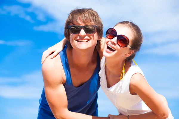 Closeup of happy young couple in sunglasses having fun on tropical beach — Stock Photo, Image