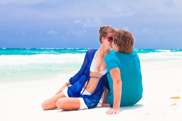 Jeune couple heureux assis et flirtant sur la plage tropicale — Photo