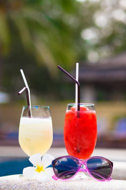 iki alkol kokteyller, güneş gözlüğü ve çiçek havuzu yakınlarında