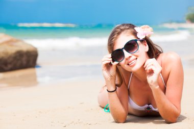 bikini ve çiçek saç tropik sahilde yatan uzun saçlı kadın