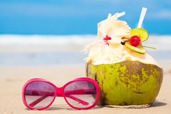 Photo de cocktail de noix de coco fraîche et lunettes de soleil rouges sur la plage tropicale — Photo