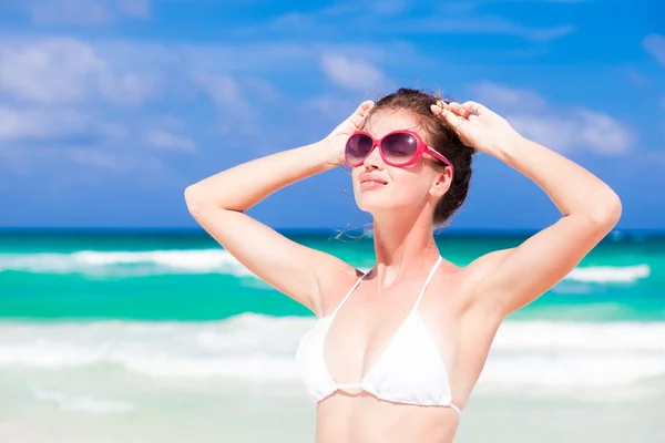 Vorderansicht der schönen jungen Frau in Bikini und Sonnenbrille, die am tropischen Strand steht und die Sonne genießt — Stockfoto