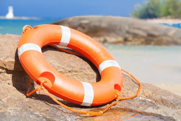 Oranje reddingsboei op rotsen op zee zijkant. levensreddende apparatuur. concept — Stockfoto