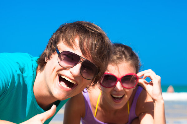 Closeup of happy young caucasian couple in sunglasses having fun on tropical beach