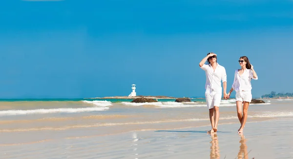 Joven pareja caucásica feliz en blanco caminando en la playa sonriendo — Foto de Stock