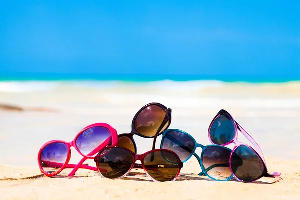 Bild många solglasögon liggande på tropical beach — Stockfoto