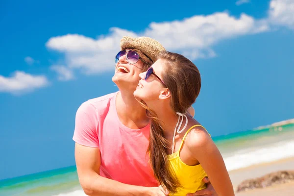 Porträt eines glücklichen jungen Paares mit Sonnenbrille, das am Strand in die Sonne blickt — Stockfoto