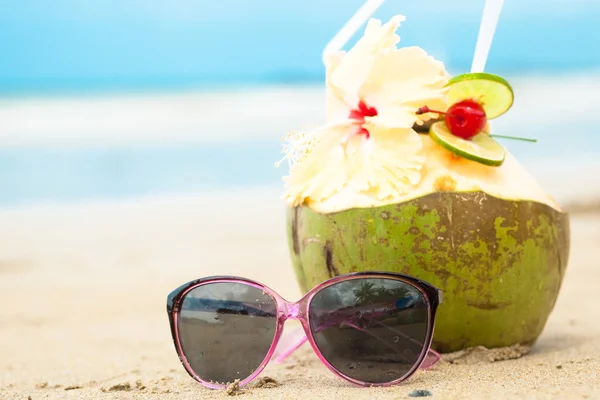 Picture of fresh cocnut cocktail and pink sunglasses on tropical beach — Stock Photo, Image
