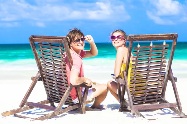 Couple in sunglasses on sun lounger on tropical beach smiling — Stock Photo, Image