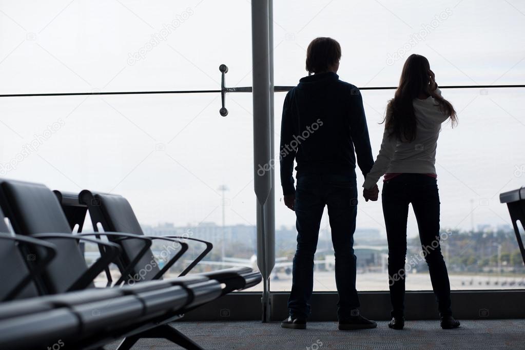 Silhouette of a couple holding hands and waiting at airport terminal