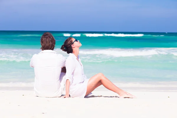 Happy νεαρό ζευγάρι με λευκά ρούχα σε γυαλιά ηλίου που βρίσκεται στην παραλία — Φωτογραφία Αρχείου