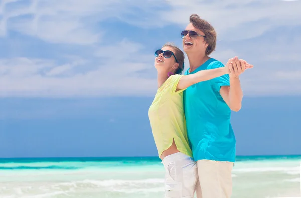 Junges Paar in hellen Kleidern genießt seine Zeit am tropischen Strand — Stockfoto
