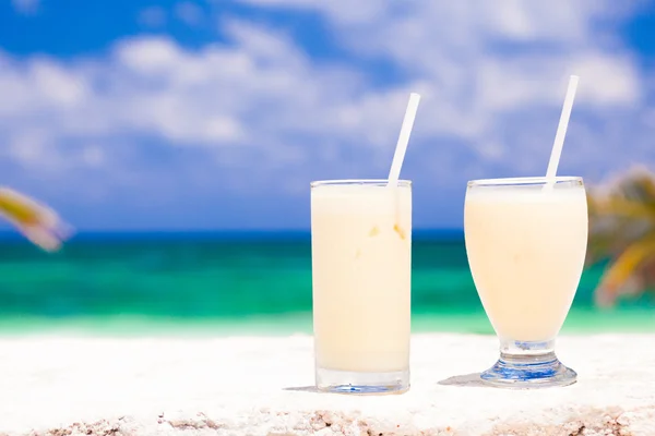 Bild von zwei weißen Cocktails am tropischen Strand mit Palmen auf dem Hintergrund — Stockfoto