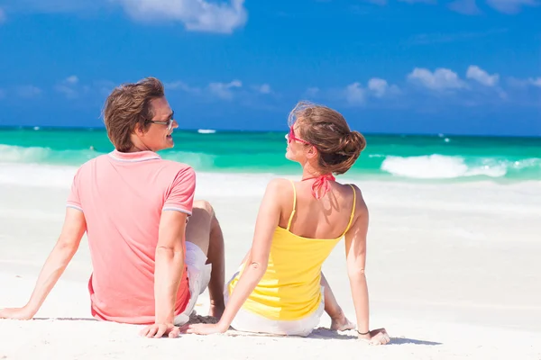 Joven pareja feliz en gafas de sol sentado en la playa tropical —  Fotos de Stock