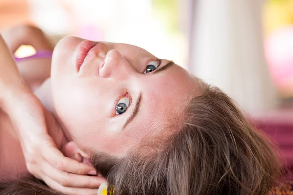 Hermosa joven recibiendo masaje facial con los ojos abiertos en un salón de spa — Foto de Stock