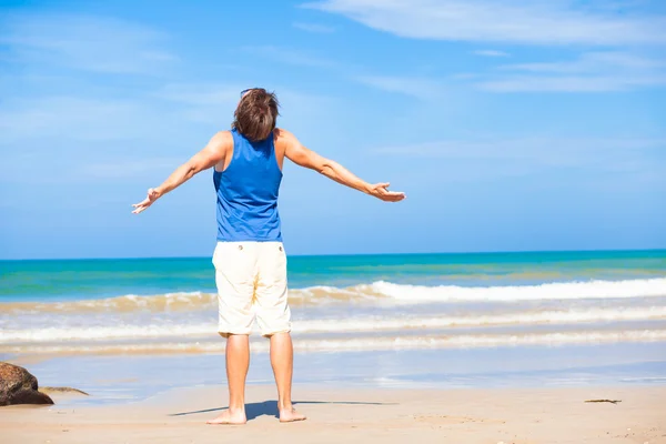 Мужчина машет руками на пляже, наслаждаясь временем загара — стоковое фото