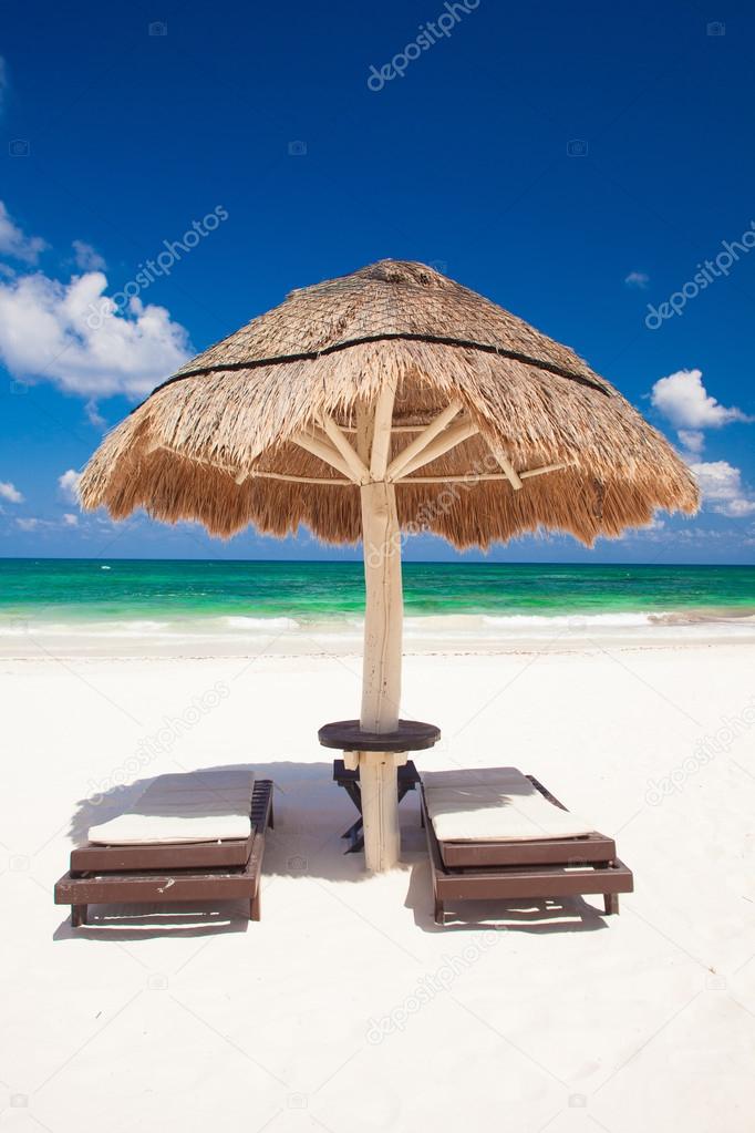 View of the tropical beach with umbrella and two beds