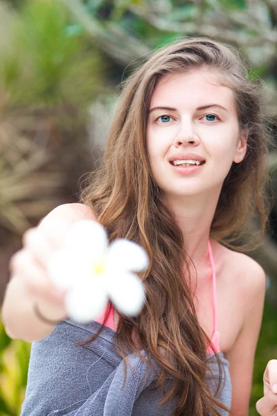 Portrait de jeune femme souriante en serviette tenant une fleur à la main — Photo