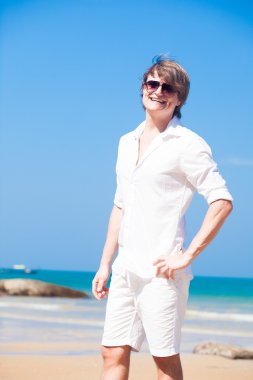 genç yakışıklı adam beyaz giysiler ve plajda güneş gözlüğü gülümseyen Önden Görünüm
