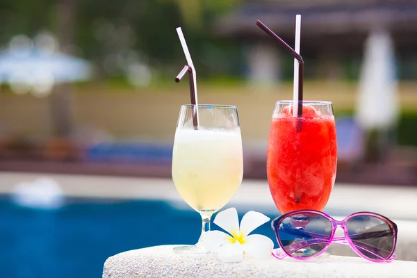 Two glasses of cocktails and sunglasses near pool — Stock Photo, Image