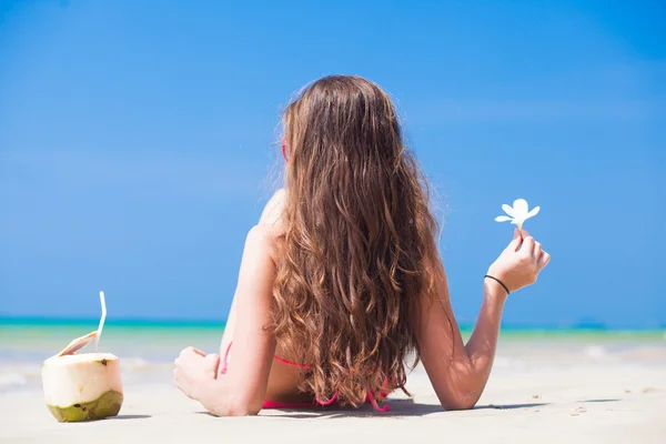 幸福的年轻女人在手持花在与椰子在沙滩上的比基尼 — 图库照片