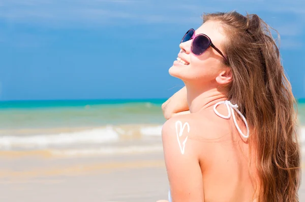 Jonge vrouw in zonnebril zetten zon crème op schouder — Stockfoto