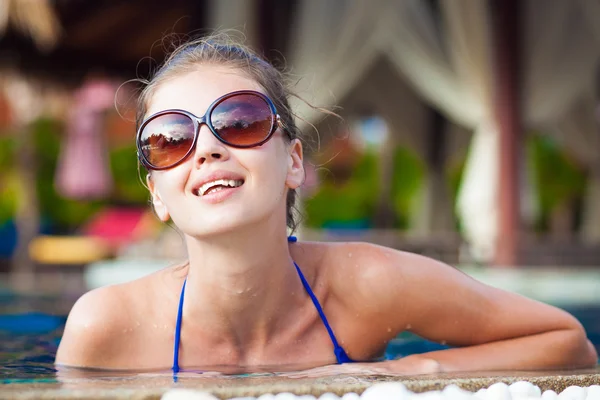 Krásná mladá žena v sluneční brýle s mokrými vlasy, usmívat se v luxusní bazén — Stock fotografie