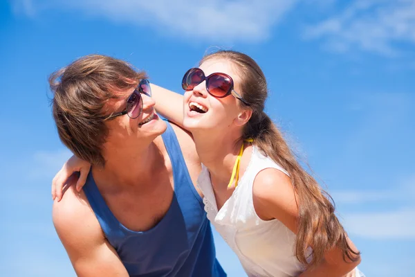 Portrait of happy young couple in sunglasses having fun on tropical beach — Stock Photo, Image