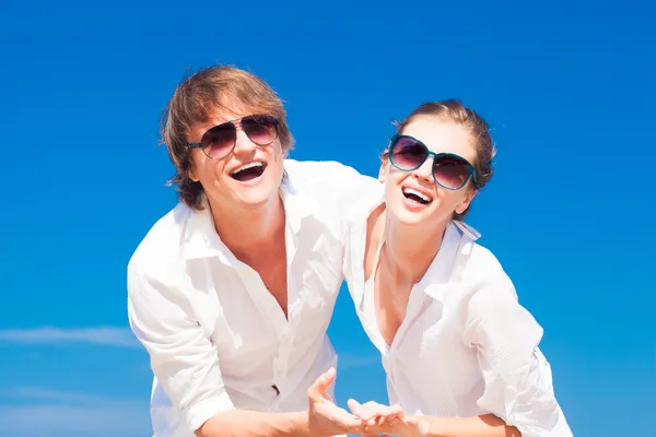 Retrato de jovem casal feliz em óculos de sol em roupas brancas sorrindo ao ar livre — Fotografia de Stock