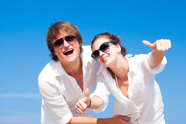 Vista frontal de la feliz pareja joven en la playa sonriendo y abrazándose. Pulgares arriba — Foto de Stock