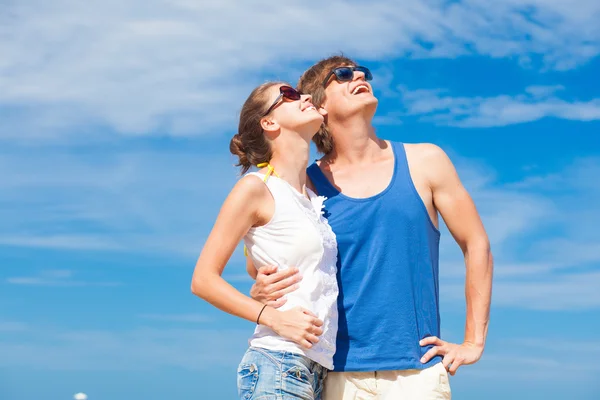 Primer plano de feliz pareja joven en gafas de sol en la playa sonriendo y mirando al cielo —  Fotos de Stock