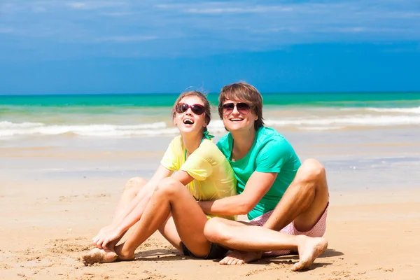 年轻幸福的夫妇坐在地处热带的海滩上的太阳镜 — 图库照片