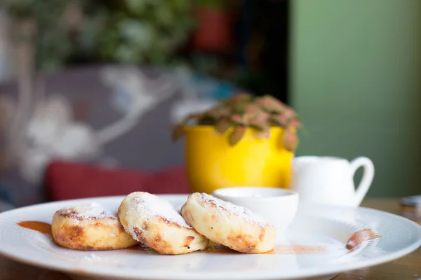 Käsepfannkuchen mit saurer Sahne auf einem weißen Teller. Frühstück — Stockfoto