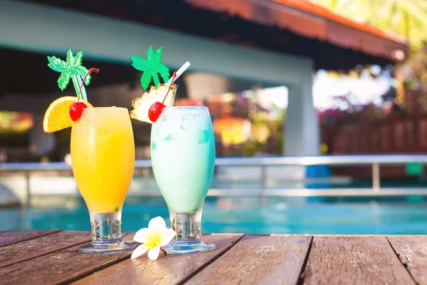 Dos copas de cócteles y flores cerca de la piscina. fiesta —  Fotos de Stock