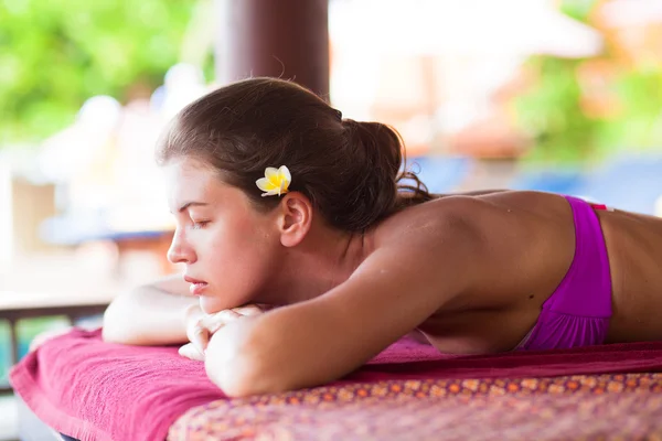 Beautiful young woman with flower in hair lying in spa — Stock Photo, Image