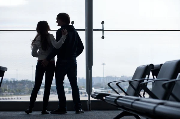 Silhouet van een paar hand in hand en te wachten op de luchthaven terminal — Stockfoto