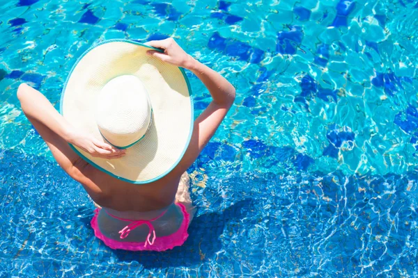 Mulher de chapéu de palha relaxante na piscina de luxo — Fotografia de Stock