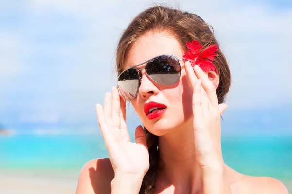 Porträt einer jungen schönen Frau mit roten Lippen und Hibiskus, — Stockfoto