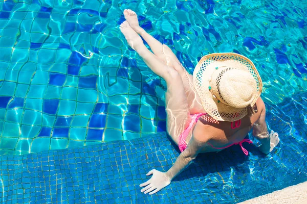 Mulher de chapéu de palha relaxante na piscina de luxo — Fotografia de Stock