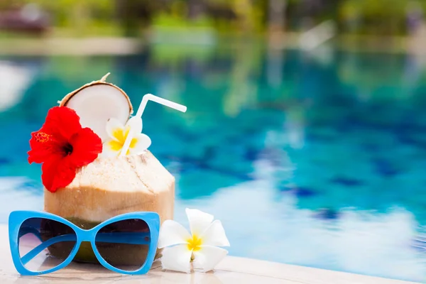 Exotischer frischer Kokosshake und Sonnenbrille am tropischen Pool — Stockfoto
