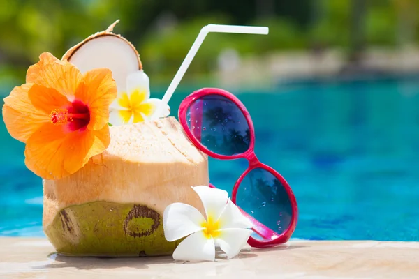 Exotischer frischer Kokosshake und Sonnenbrille am tropischen Pool — Stockfoto