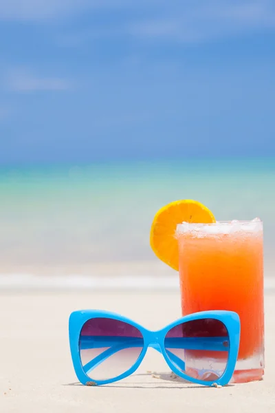 Cocktail de fruta fresca com óculos azuis na praia tropical — Fotografia de Stock