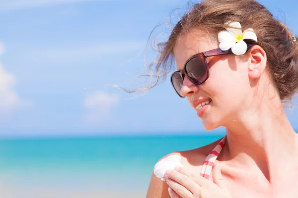 Jeune femme en lunettes de soleil mettant crème solaire sur l'épaule — Photo