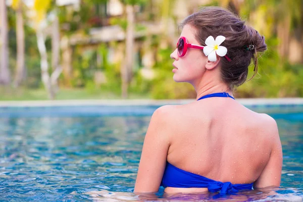 Half face portrait of young attractive woman relaxing at tropical pool — Stock Photo, Image