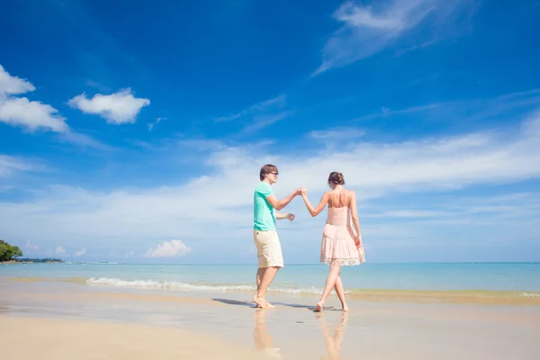 Ritratto di giovane coppia felice in abiti luminosi e occhiali da sole che si diverte sulla spiaggia tropicale — Foto Stock