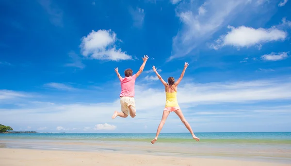 Portrait of happy young couple in bright clothes and sunglasses having fun on tropical beach — Stock Photo, Image