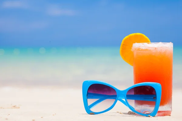 Cóctel de frutas frescas con gafas de sol azules en la playa tropical —  Fotos de Stock