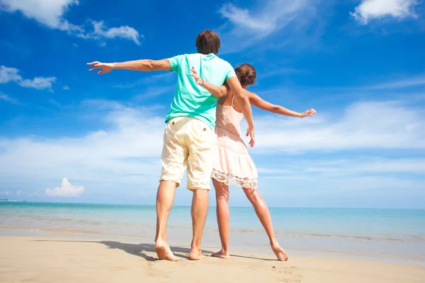 Porträt eines glücklichen jungen Paares in heller Kleidung und Sonnenbrille, das Spaß am tropischen Strand hat — Stockfoto