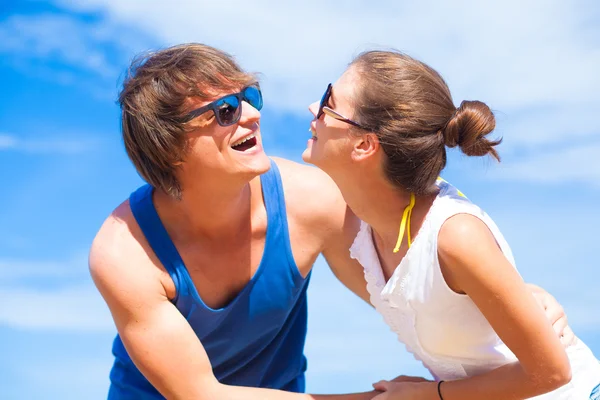 Retrato de pareja joven y feliz en gafas de sol divirtiéndose en la playa tropical —  Fotos de Stock