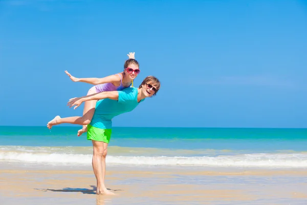 Casal feliz piggybacking em férias na praia tropical — Fotografia de Stock